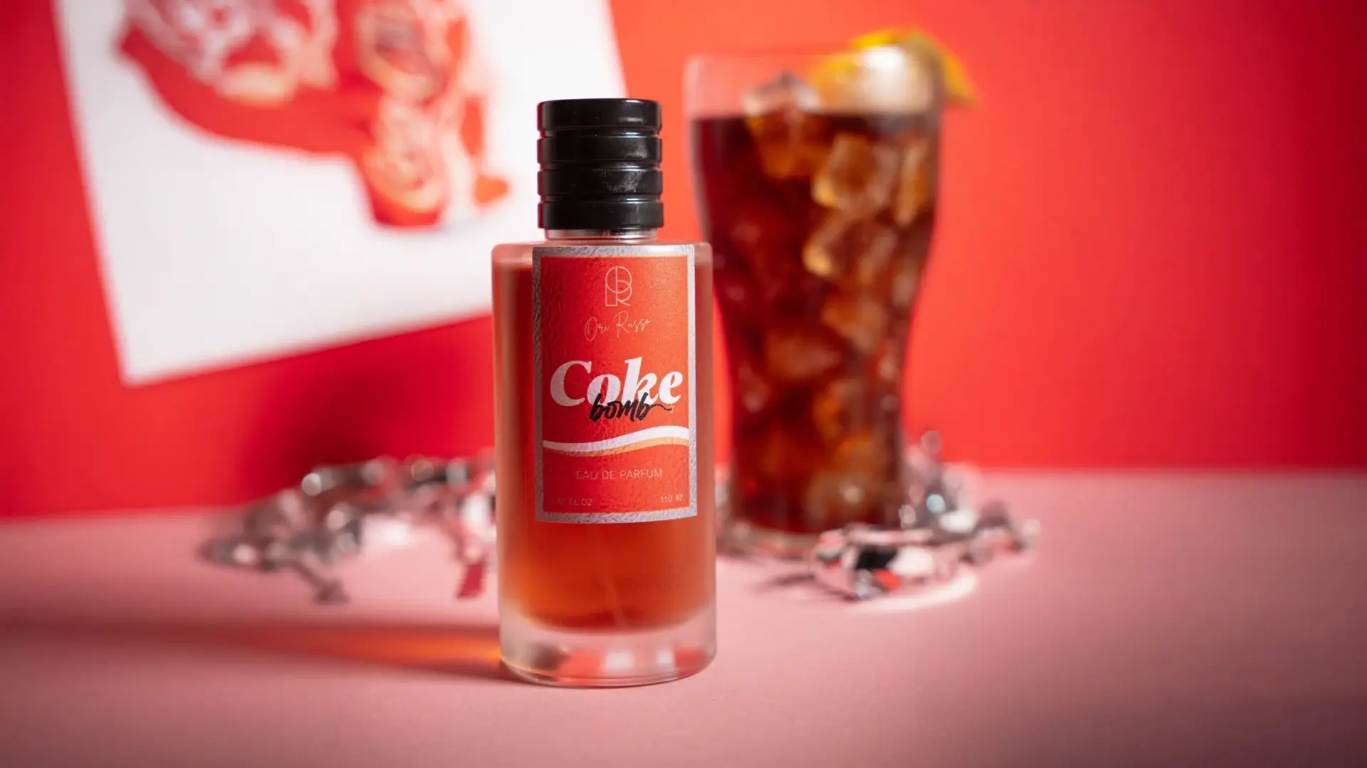 Fragancia de Ori Ruso de Coca Cola sobre un fondo rojo y un vaso de Cola