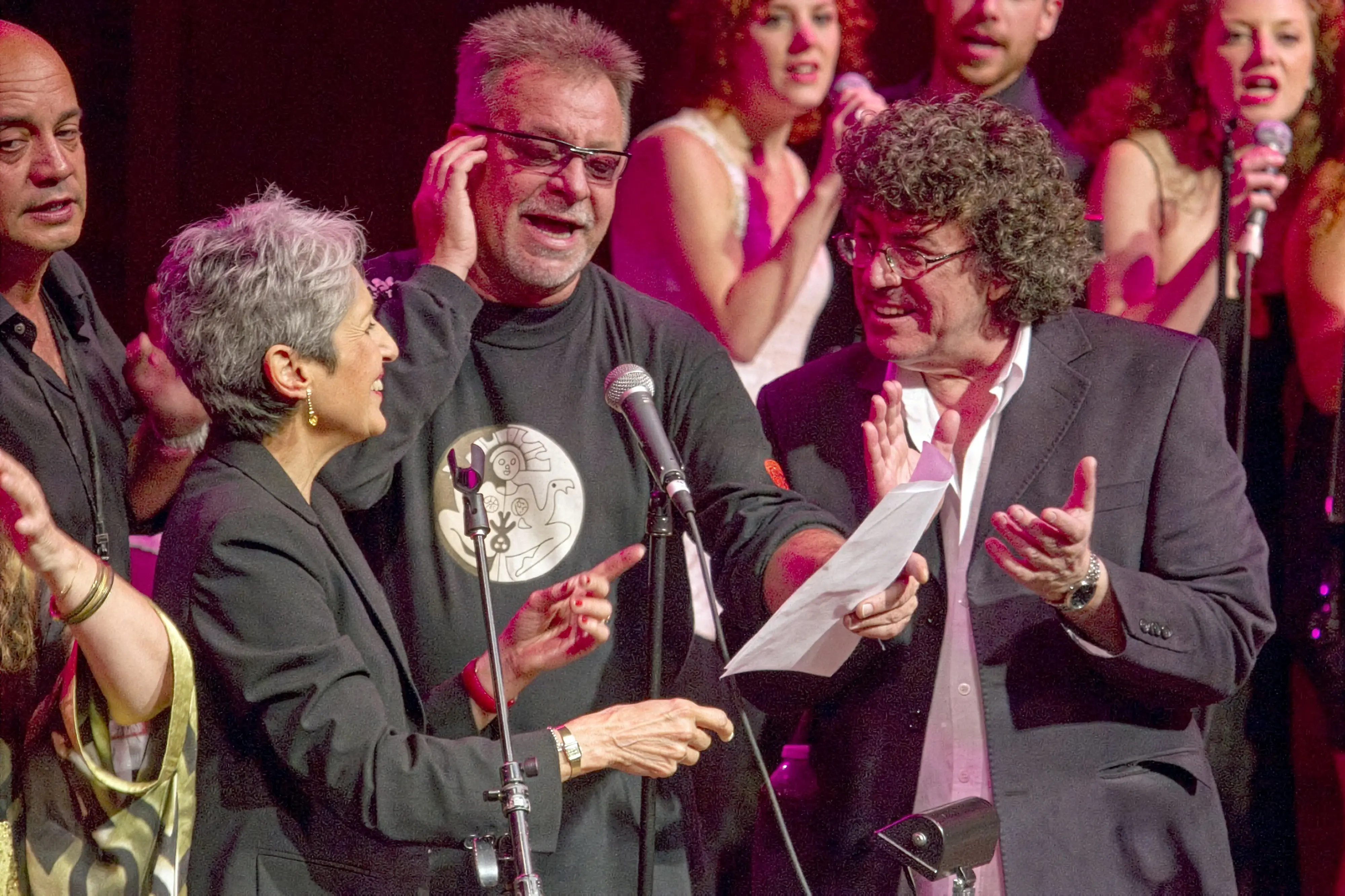 Piero en un escenario con otras dos personas frente a un micrófono