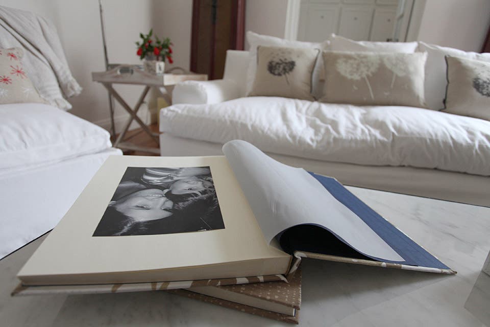 Sobre la mesa ratona, uno sobre otro, álbumes de fotos verticales, de 25 x 35 cm, en género estampado a tono con la ambientación, interior de 30 hojas y calcos separadores (desde $280, Buffet de Papel). En la imagen en blanco y negro, Mariana con uno de sus sobrinos