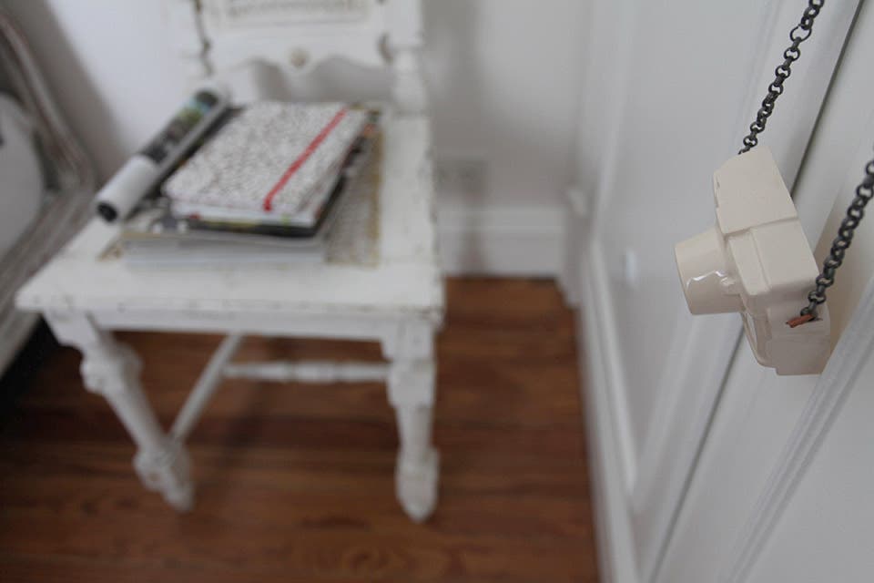 A la silla suelta junto a la cama se le dio un nuevo uso como segunda mesa de luz. Sobre ella, revistas y libretas de género con interior de 80 hojas en papel importado (desde $79, Buffet de Papel). En primer plano, cámara de fotos en gres y cuero con cadena ($75, Artefactos)