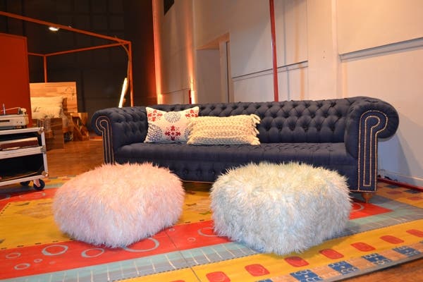 Un imponente sillón capitoné en azul se roba todas las miradas en el espacio de Diamante Sillones. A sus pies, dos pufs peluditos suman diseño