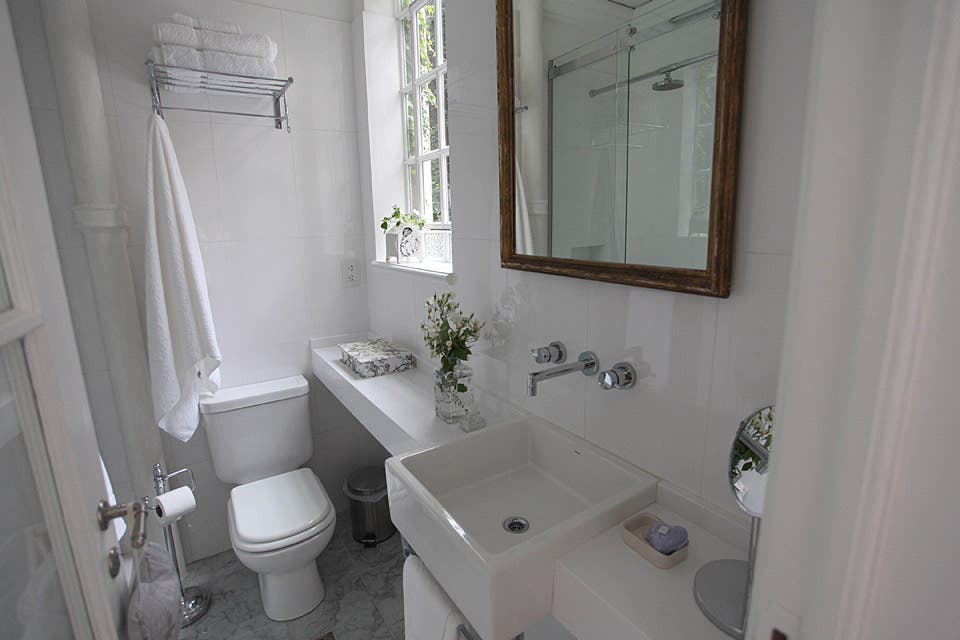 El baño combina lo antiguo con lo moderno: se mantuvieron las aberturas, el piso, las molduras y la columna de desagüe que se dejó a la vista. Aprovechando al máximo cada espacio, se colocó sobre el inodoro un rack para toallas