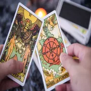 Dos cartas de tarot sostenidas por una mano.