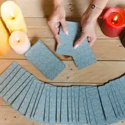 Unas manos con cartas de tarot y un mazo de tarot desplegado sobre una mesa.