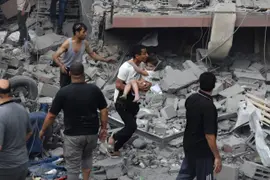 Un palestino lleva a un niño rescatado de la casa de la familia Tattari, que fue destruida en un ataque aéreo israelí en la ciudad de Gaza el 9 de octubre de 2023. Entre los muertos hay 4 argentinos; al menos otros 4 están desaparecidos.