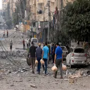 Hombres palestinos llevan pan a través de una calle fuertemente bombardeada después de los ataques aéreos israelíes en la ciudad de Gaza el 10 de octubre de 2023.