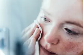 Mujer pasándose un tónico por la cara.