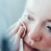 Mujer pasándose un tónico por la cara.