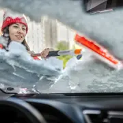 Mujer descongelando el parabrisas.