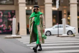 Mujer caminando con trench por la calle.