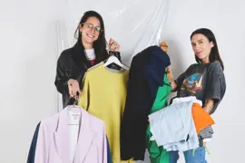 Dos chicas sosteniendo perchas con ropa.