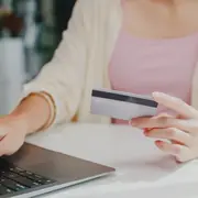 Una mujer haciendo una compra online con una tarjeta de crédito en la mano