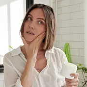 Una mujer mirándose al espejo mientras se hace su rutina de skin care