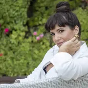 Griselda Siciliani sentada en un sillón en el jardín de su casa y rodeada de plantas