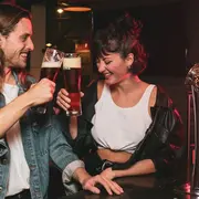 Pareja brindando con cerveza y riendo.