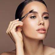 Una mujer peinándose las cejas con un cepillo