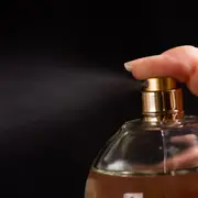 Una mano presionando un perfume