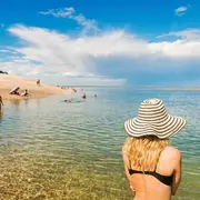 Una mujer en la playa de espaldas con un sombrero