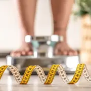 Los pies de una mujer sobre una balaza y un centímetro en primer plano.