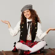 Margarita sentada sobre un baúl, con las manos abiertas.