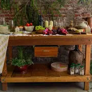 En esta imagen, el rincón completo: ladrillos a la vista, ramitas y una mesa antigua colmada de objetos de ayer y de hoy