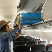 Una mujer con un carry on en el avión