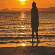 Una chica entrando al mar en un atardecer.