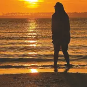 Una chica entrando al mar en un atardecer.