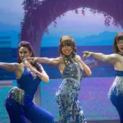 Tres mujeres cantando en un escenario.