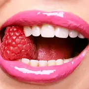 Una mujer comiendo una frambuesa