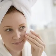 Una mujer haciéndose el skin care frente al espejo