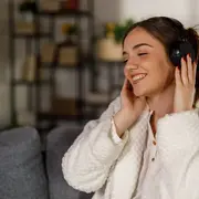 Una mujer escuchando musica desde sus auriculares en el sillón de su casa