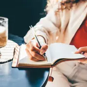 Una mujer escribiendo en un cuaderno.