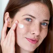 Una mujer poniendose crema en el rostro