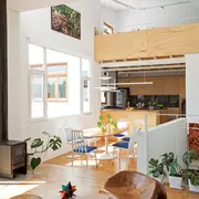 Un pequeño desnivel refuerza la transición entre el living y el comedor, con mesa 'Tulip' con tapa ovalada de madera y sillas con tapizado azul que combinan el modelo 'Tulip' con otras tipo Windsor. En primer plano, asiento tallado en madera del escultor Jorge Michel.