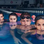 4 actores sumergidos en una pileta de natación.
