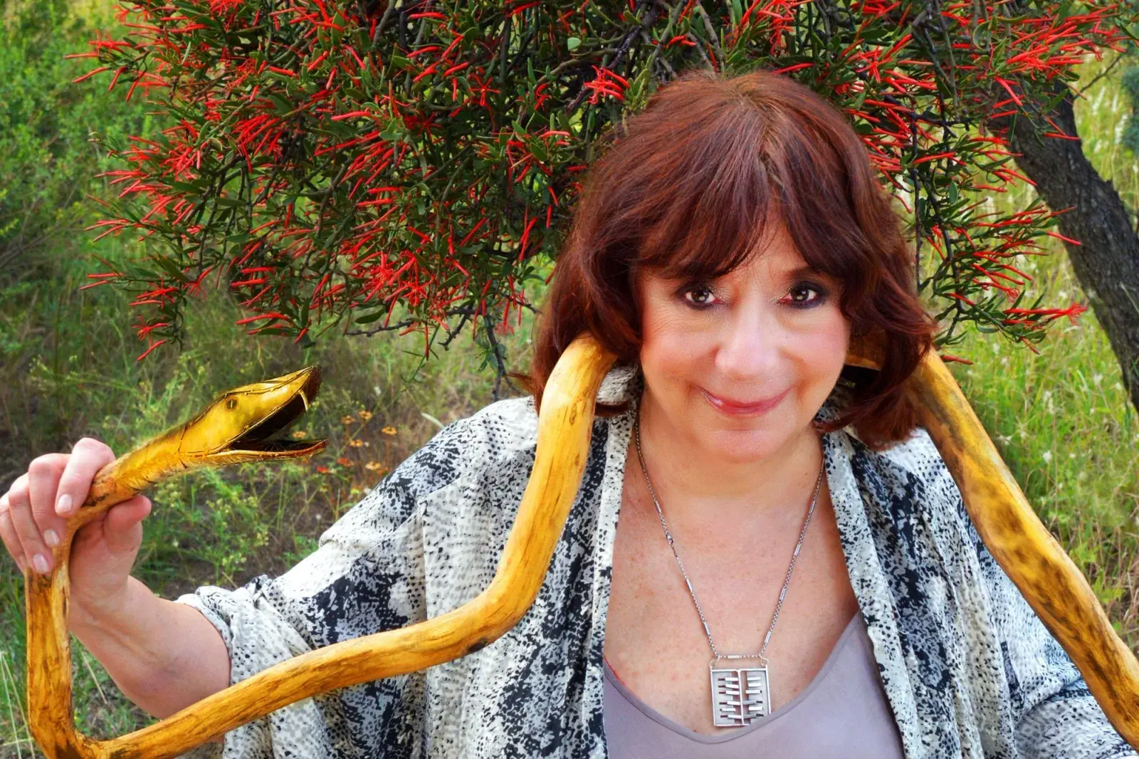 Ludovica Squirru sostiene una serpiente de oro en un fondo arbolado