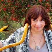 Ludovica Squirru sostiene una serpiente de oro en un fondo arbolado