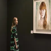 Chloe mirando a la pared dónde hay un cuadro de pintura de una mujer colorada