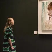 Chloe mirando a la pared dónde hay un cuadro de pintura de una mujer colorada