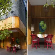 Una galería en sintonía con el entorno exterior y que simula un espacio interior. Ambientando como un living, con sillas vintage de estilo MDQ y un elemento estratégico: el espejo redondo que refleja la naturaleza sobre la fachada en madera.