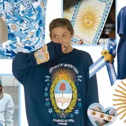Collage de distintas prendas y accesorios con temática argentinidad. Se ve un Sol de mayo, un listón con la bandera de Argentina. En el centro una chica sonriendo con un buzo de Argentina
