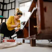 Foto de mujer reparando un mueble antiguo.