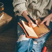 Mujer escribiendo metas en libro.