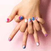 Dos manos entrelazadas con uñas de colores
