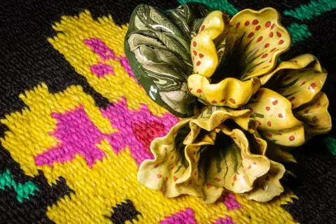 Elementos argentinos: alfombra intervenida con la una flor de cerámica de Nicola Costantino. Elementos argentinos: alfombra intervenida con la una flor de cerámica de Nicola Costantino.