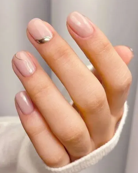 También es una re opción combinar las milky nails con diseños no lineales en color dorado o plateado.