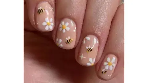 Nail art con mini abejas y margaritas sobre un fondo color nude Nail art con mini abejas y margaritas sobre un fondo color nude