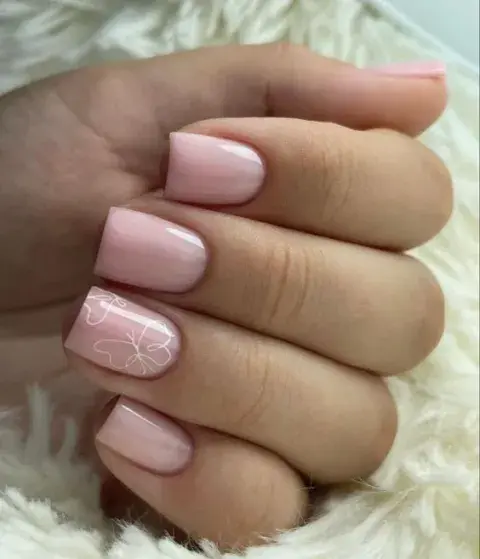 Un diseño con esmalte rosa y una mariposa dibujada en color blanco y líneas finas. Muy delicado.