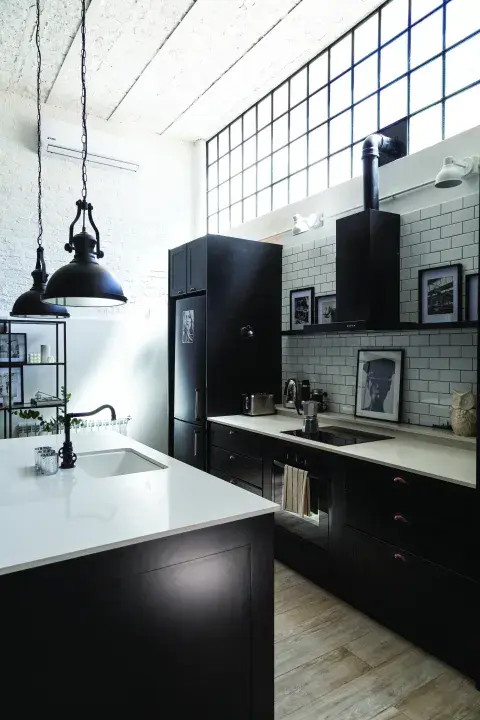 Cocina open concept con detalles de estilo neoyorquino: blanco y negro, vidrio repartido, azulejos subway y arte. 